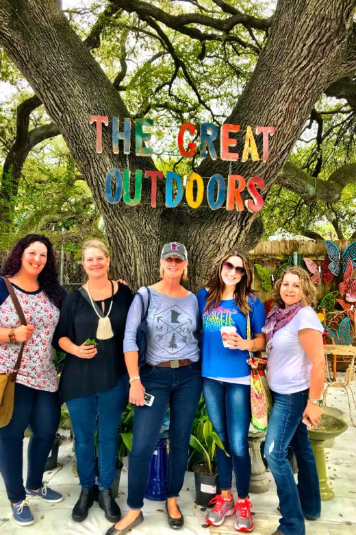 Group posed under a sign reading The Great Outdoors Outdoo