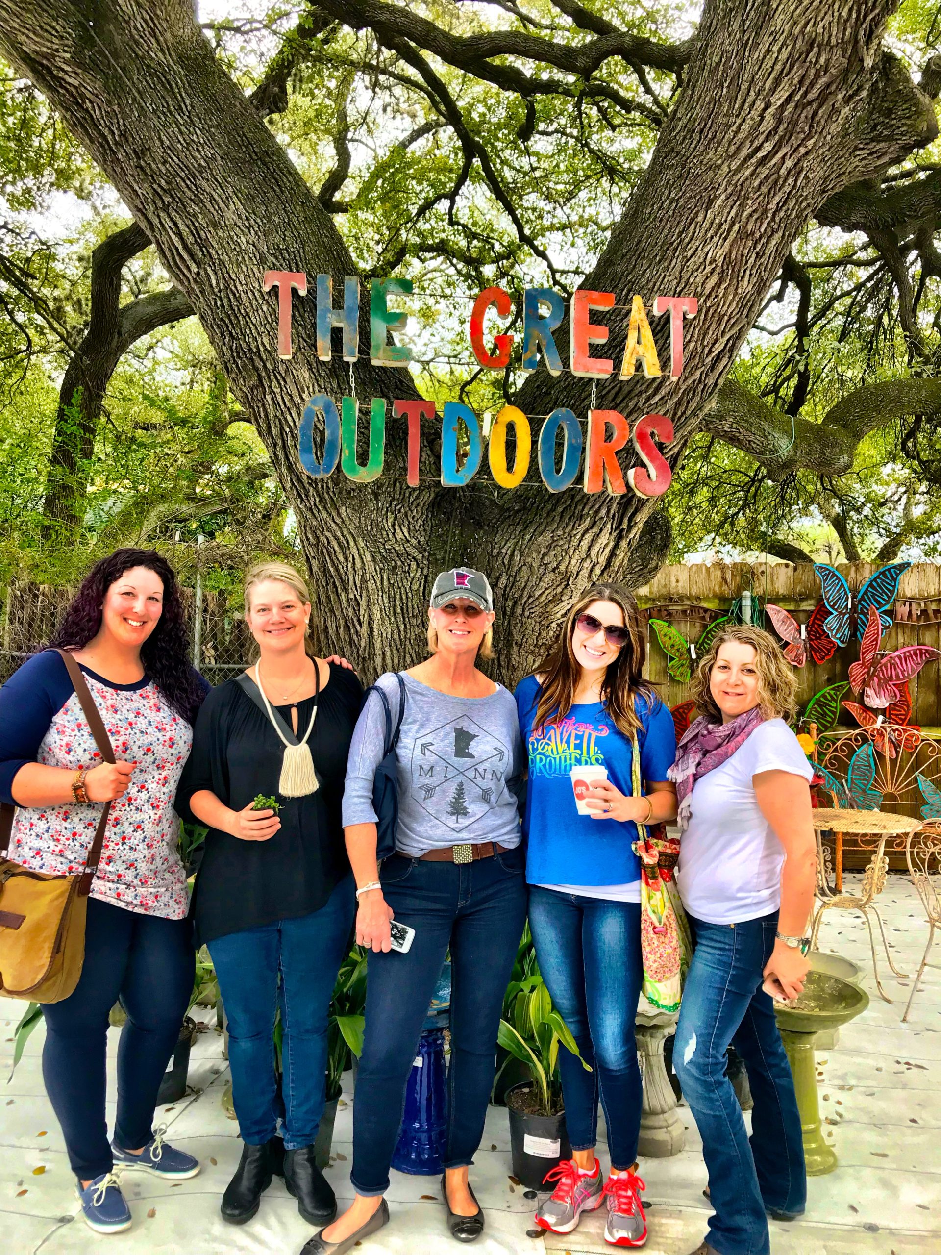 Group posed under a sign reading The Great Outdoors Outdoo